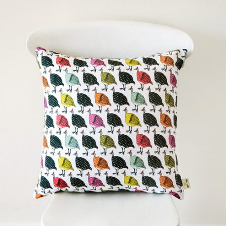 A handmade cushion featuring a fun design with rows of vintage coloured guinea birds on a white chair